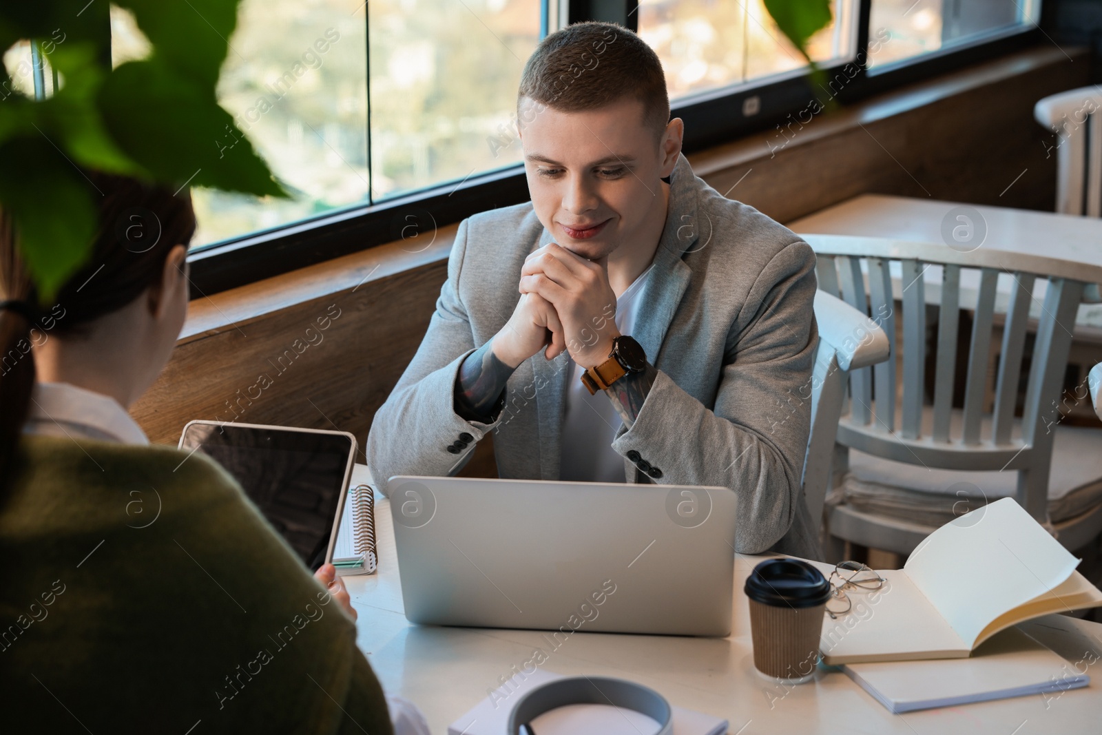 Photo of Young students with laptop and tablet studying at table in cafe