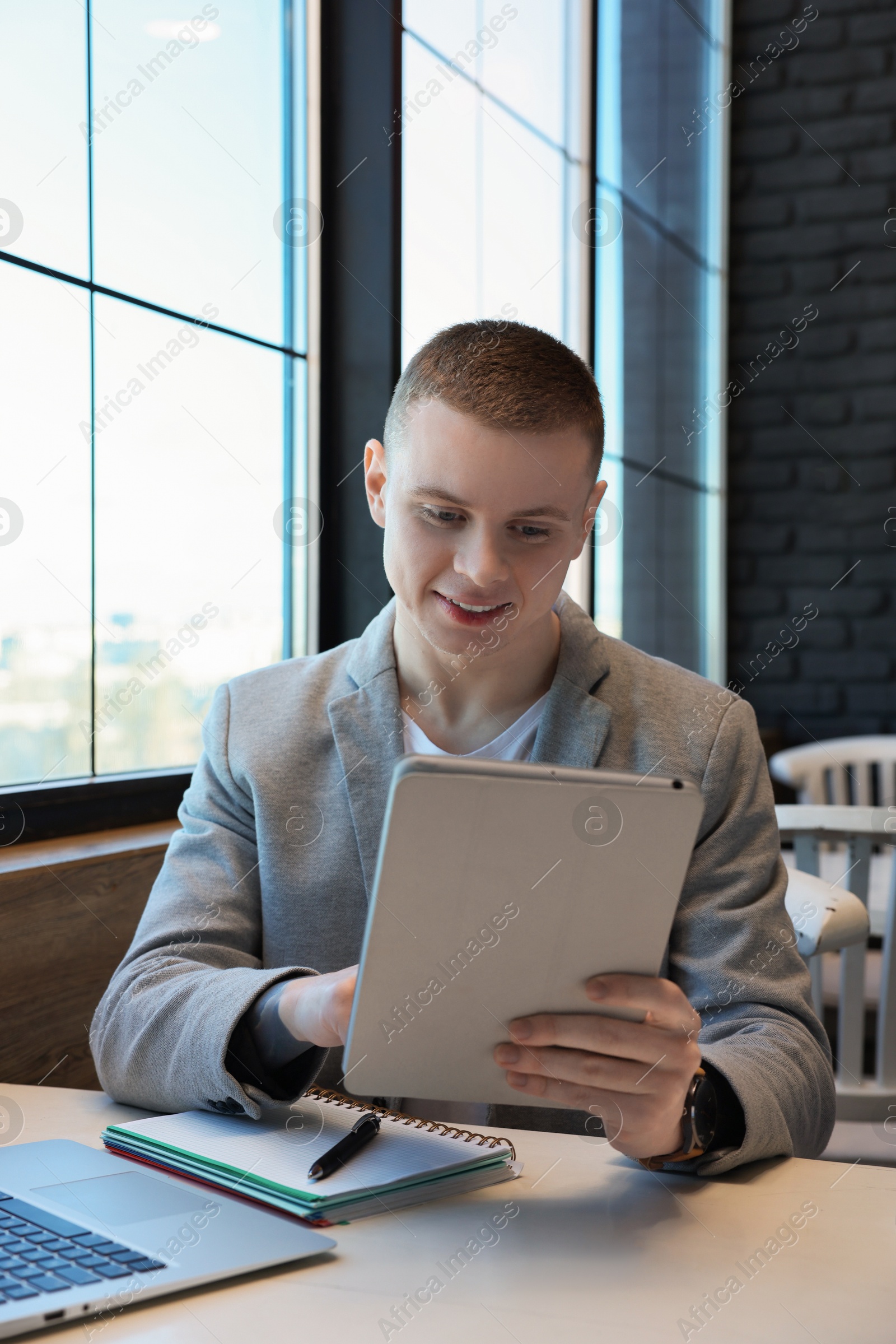 Photo of Young male student with tablet studying at table in cafe