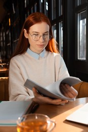 Young female student studying at table in cafe