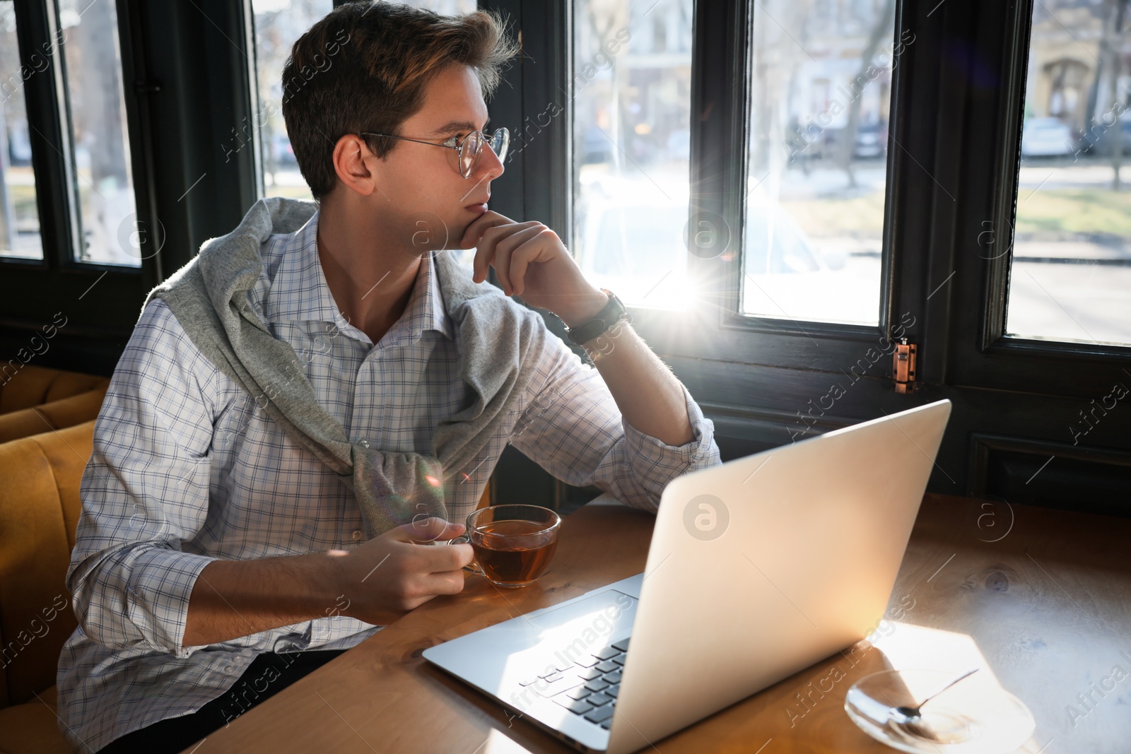 Photo of Teenage student with laptop studying at table in cafe