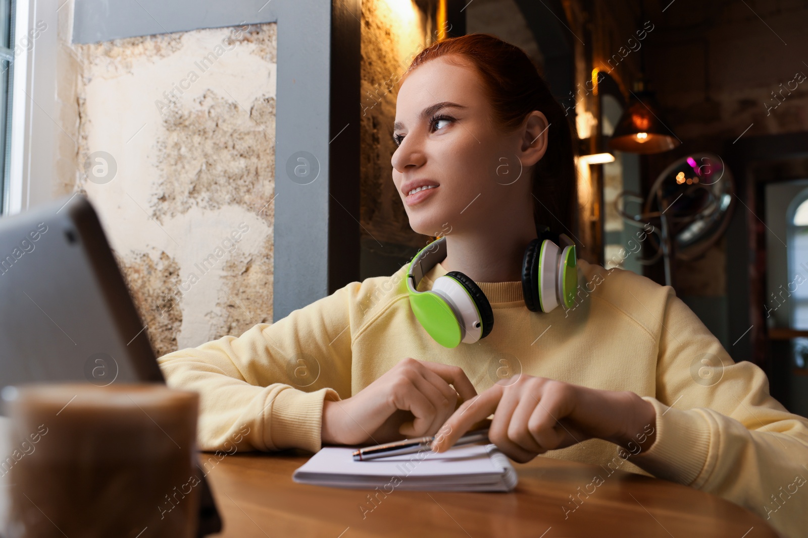 Photo of Young female student with tablet studying at table in cafe