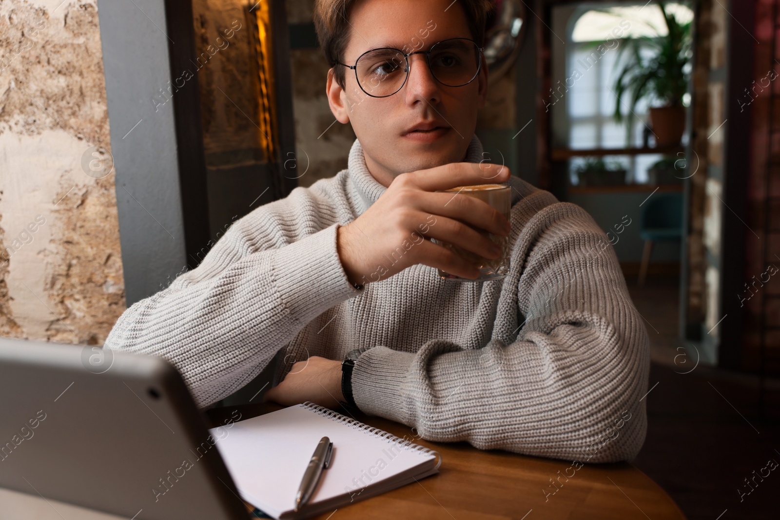 Photo of Teenage student with coffee studying at table in cafe