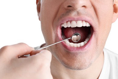 Photo of Dentist examining man's teeth and gums with mirror on white background, closeup