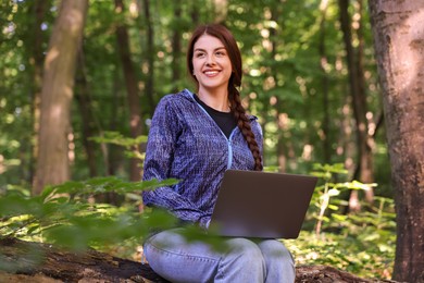 Smiling freelancer working with laptop in forest. Remote job