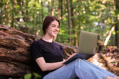 Smiling freelancer working with laptop in forest. Remote job