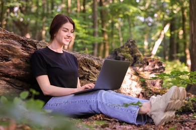 Smiling freelancer working with laptop in forest, low angle view. Remote job