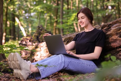 Smiling freelancer working with laptop in forest, low angle view. Remote job