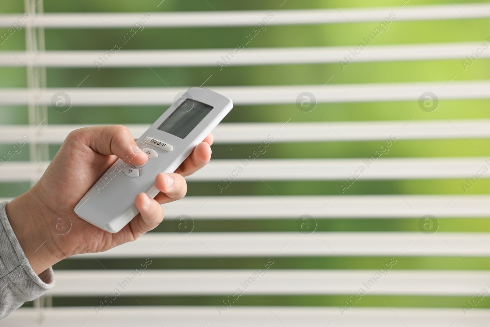 Photo of Man using remote control to adjust window blinds indoors, closeup. Space for text