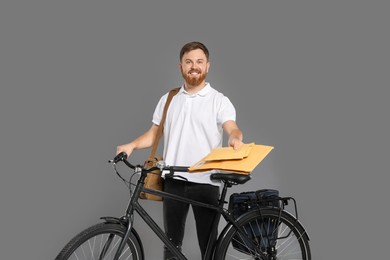 Photo of Postman with bicycle delivering letters on grey background