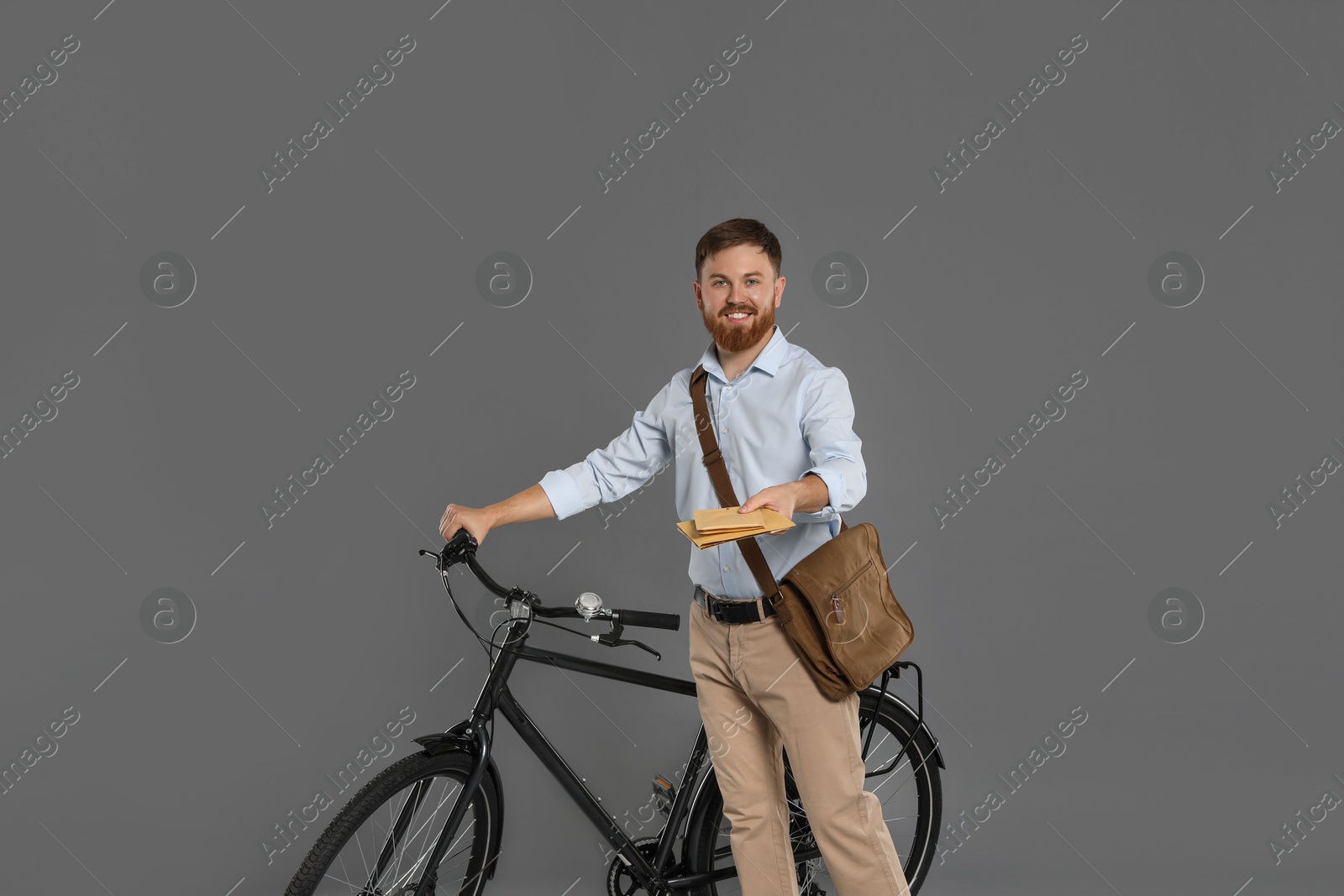 Photo of Postman with bicycle delivering letters on grey background