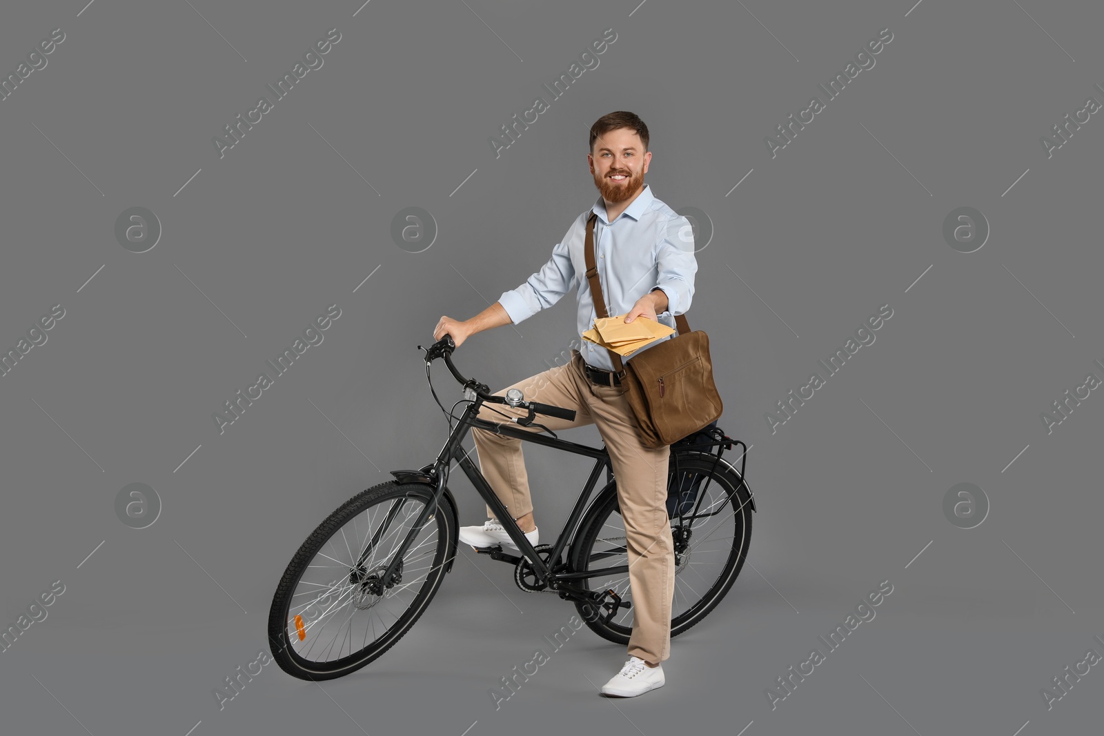 Photo of Postman on bicycle delivering letters against grey background