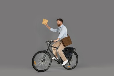 Postman on bicycle delivering letters against grey background