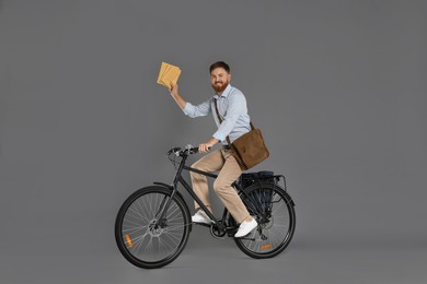 Photo of Postman on bicycle delivering letters against grey background