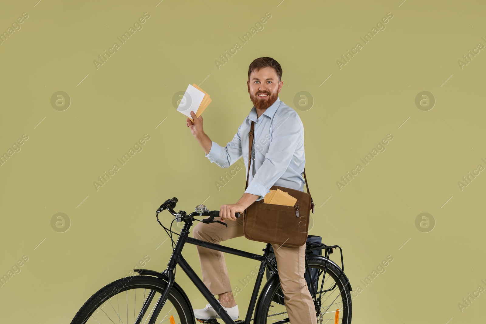 Photo of Postman on bicycle delivering letters against light green background