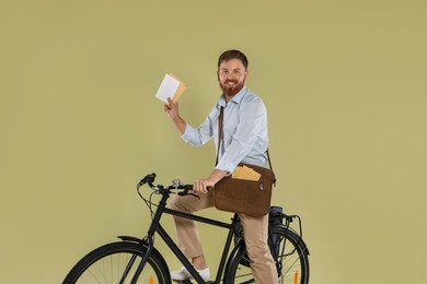 Postman on bicycle delivering letters against light green background