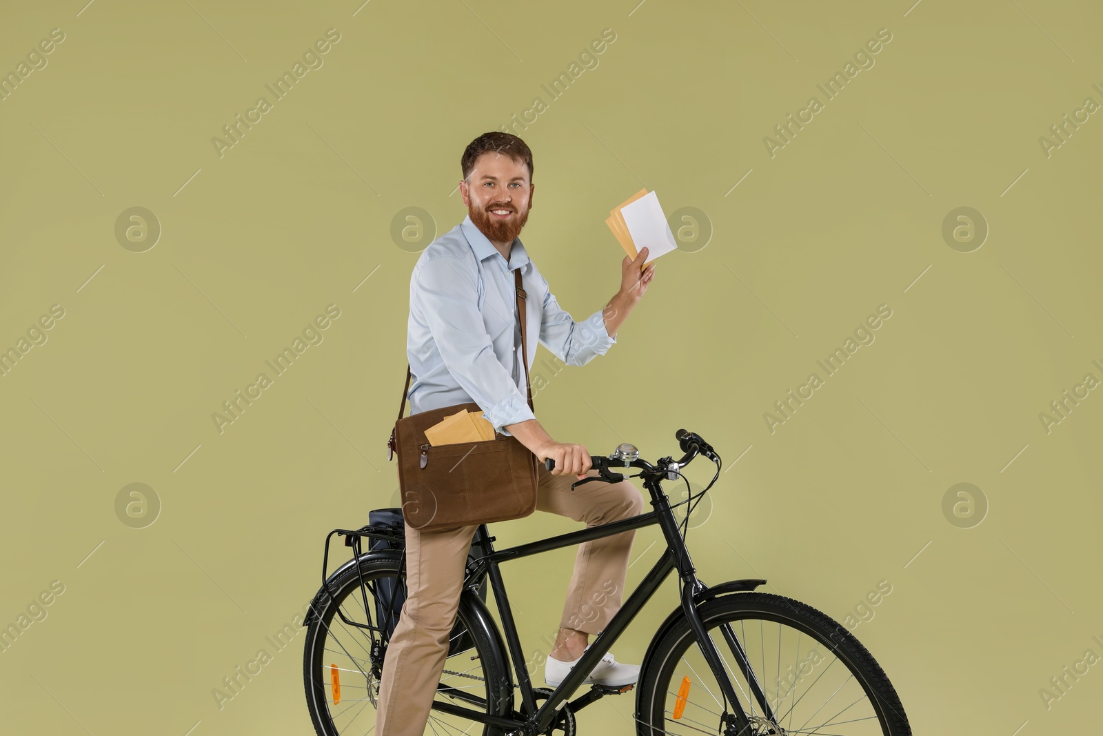 Photo of Postman on bicycle delivering letters against light green background