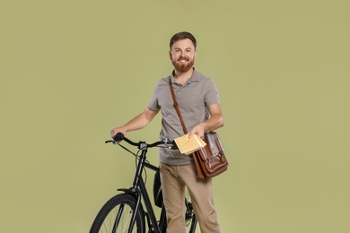 Photo of Postman with bicycle delivering letters on light green background