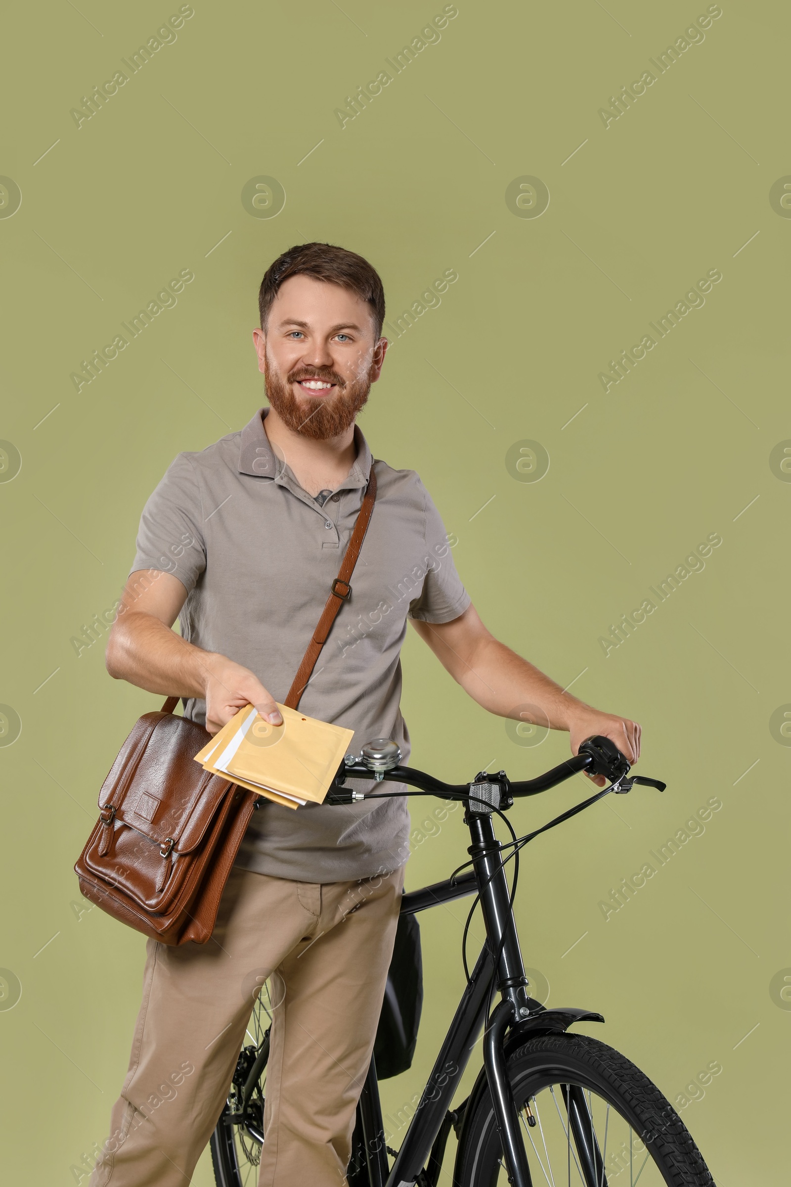 Photo of Postman with bicycle delivering letters on light green background