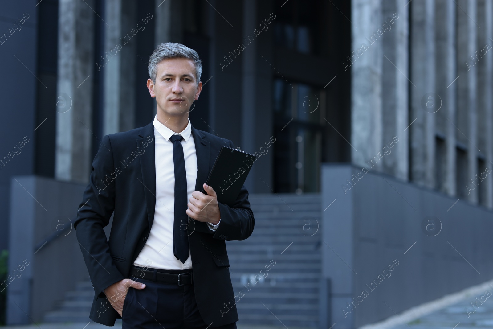 Photo of International relations. Diplomat with clipboard in suit outdoors, space for text