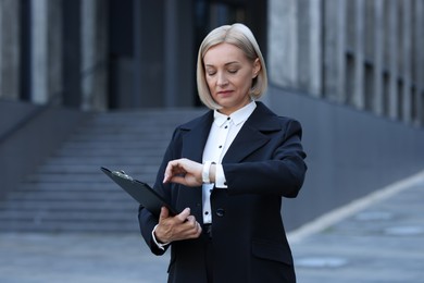 Photo of International relations. Diplomat with clipboard in suit outdoors