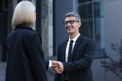 Photo of International relations. Diplomats shaking hands during meeting outdoors