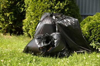 Photo of Trash bags full of garbage on green grass outdoors