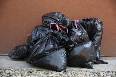 Photo of Many trash bags full of garbage outdoors