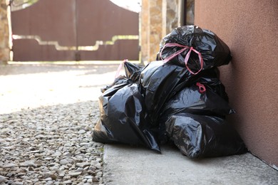 Photo of Many trash bags full of garbage outdoors, space for text