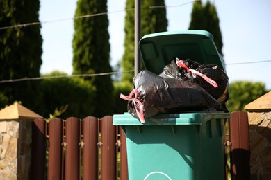 Photo of Trash bags full of garbage in bin outdoors