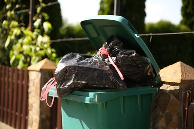 Photo of Trash bags full of garbage in bin outdoors