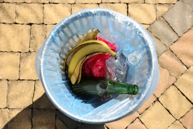 Photo of Trash bag with garbage in bin outdoors, top view