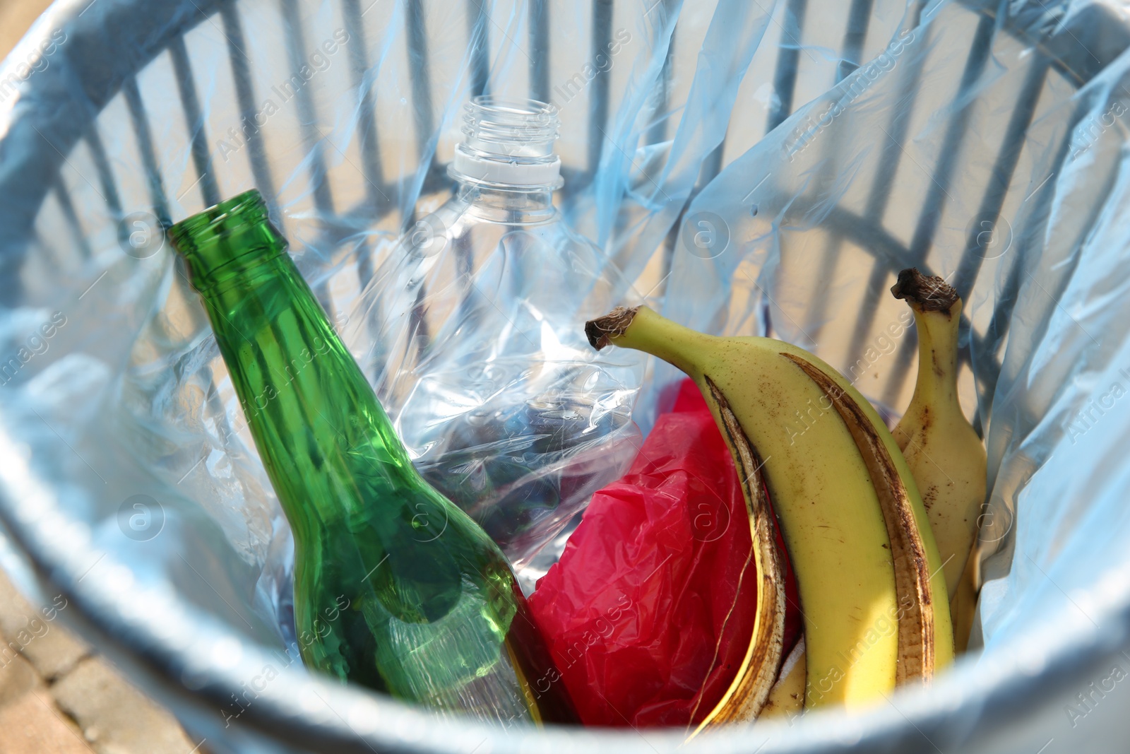 Photo of Trash bag with garbage in bin outdoors, closeup