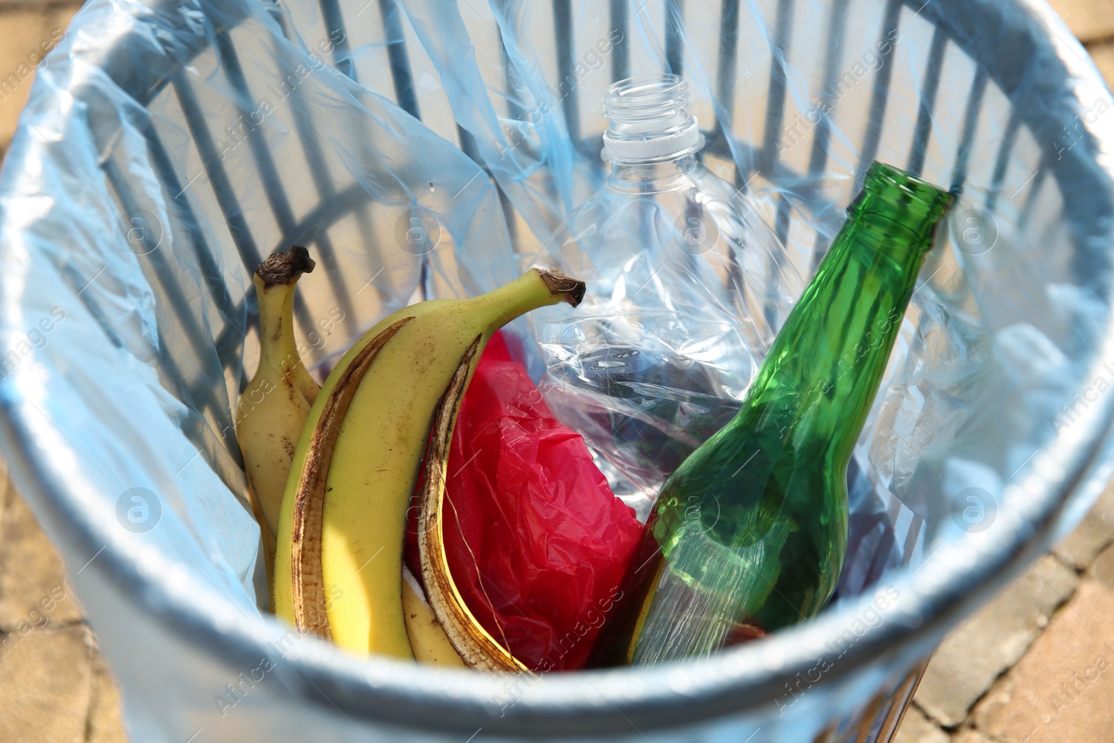 Photo of Trash bag with garbage in bin outdoors, closeup