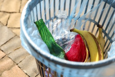 Photo of Trash bag with garbage in bin outdoors, closeup