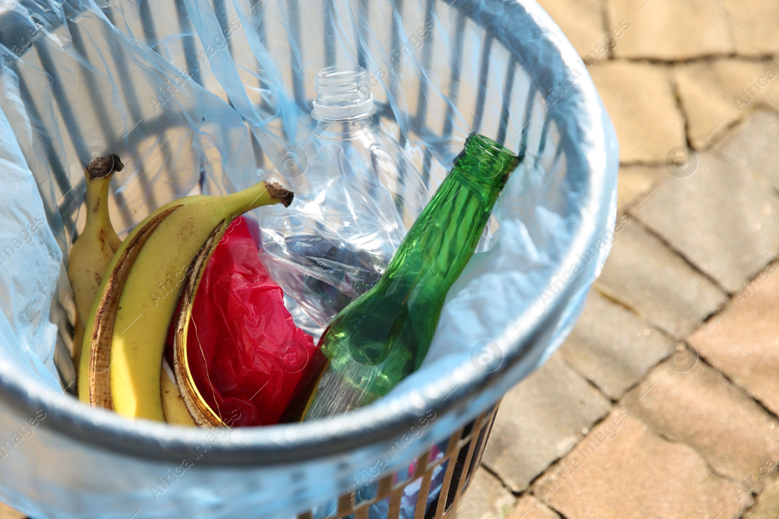 Photo of Trash bag with garbage in bin outdoors, closeup