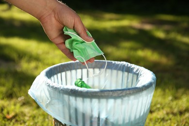 Photo of Man throwing medical mask into garbage bin outdoors, closeup