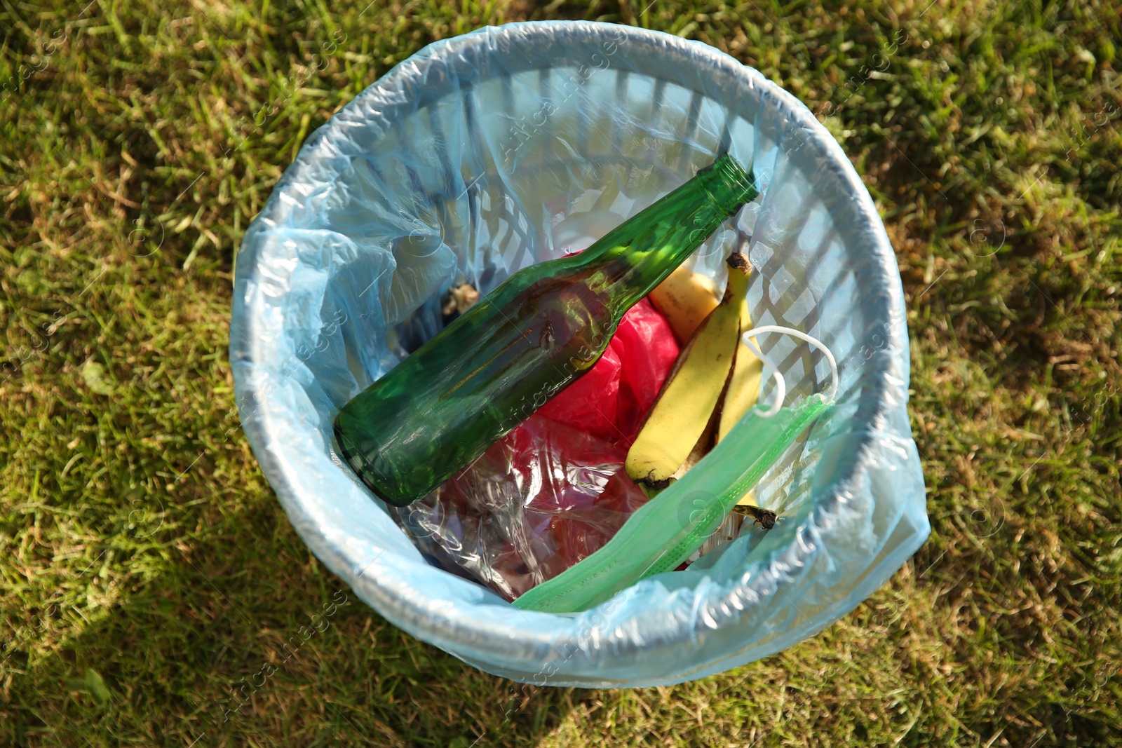 Photo of Trash bag with garbage in bin outdoors, top view