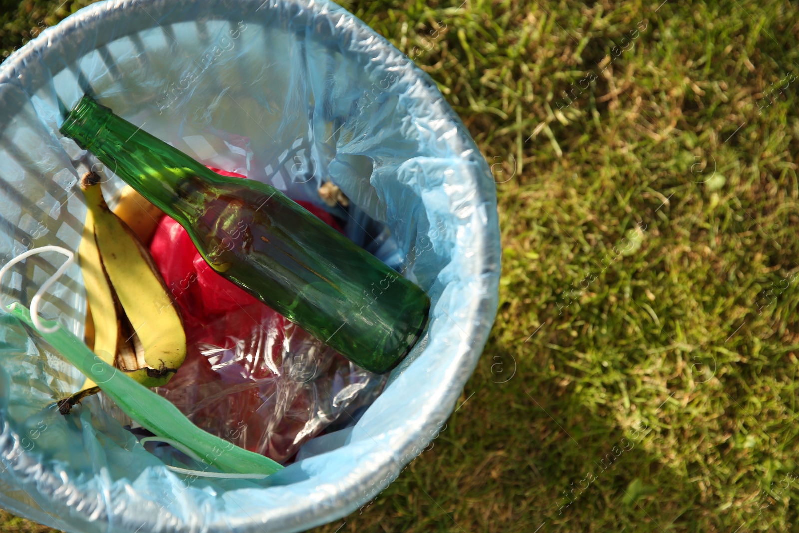 Photo of Trash bag with garbage in bin outdoors, top view. Space for text