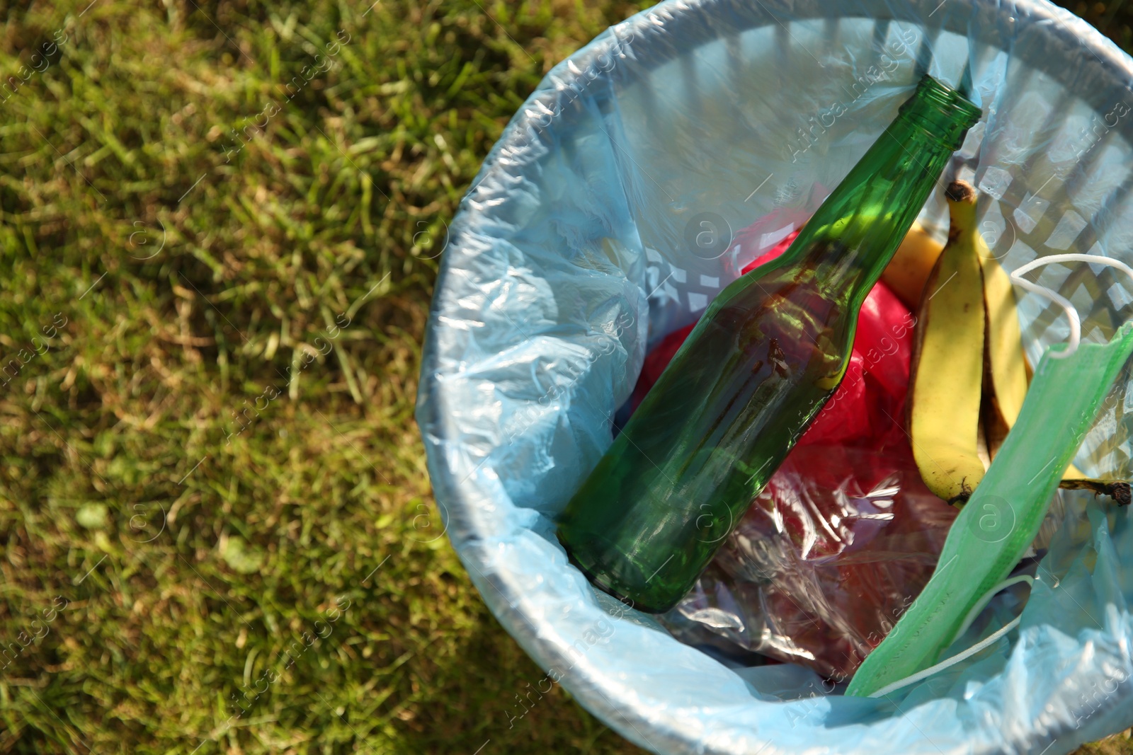 Photo of Trash bag with garbage in bin outdoors, top view. Space for text