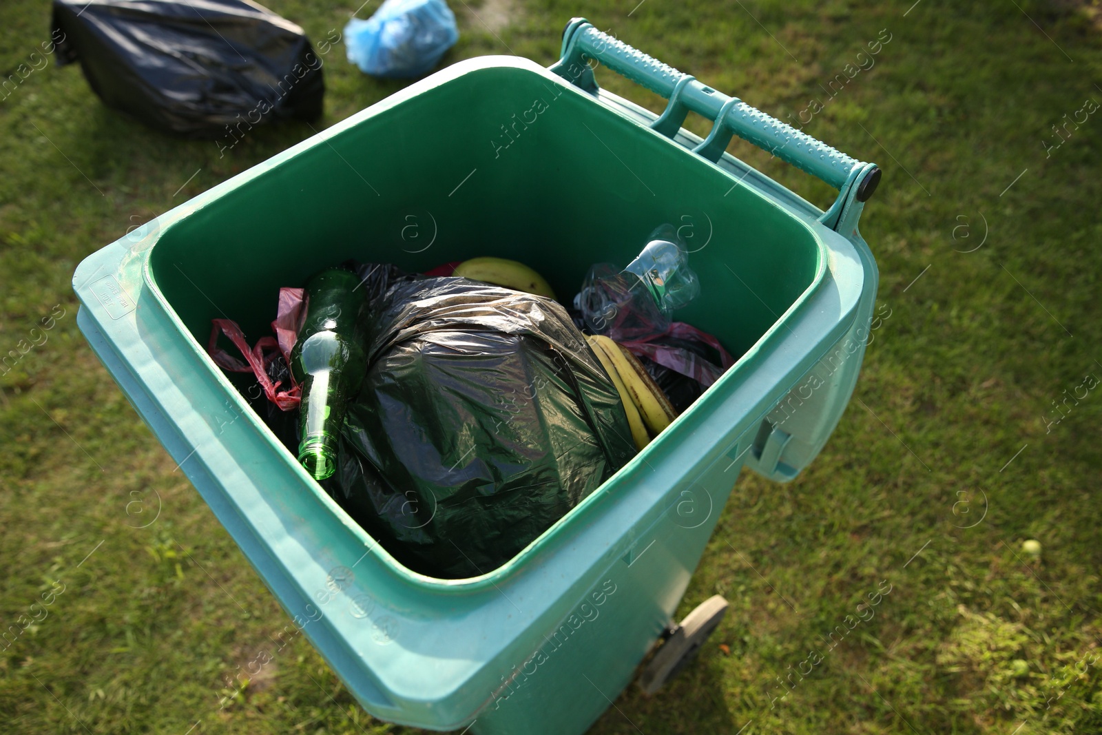 Photo of Trash bags full of garbage in bin outdoors, closeup