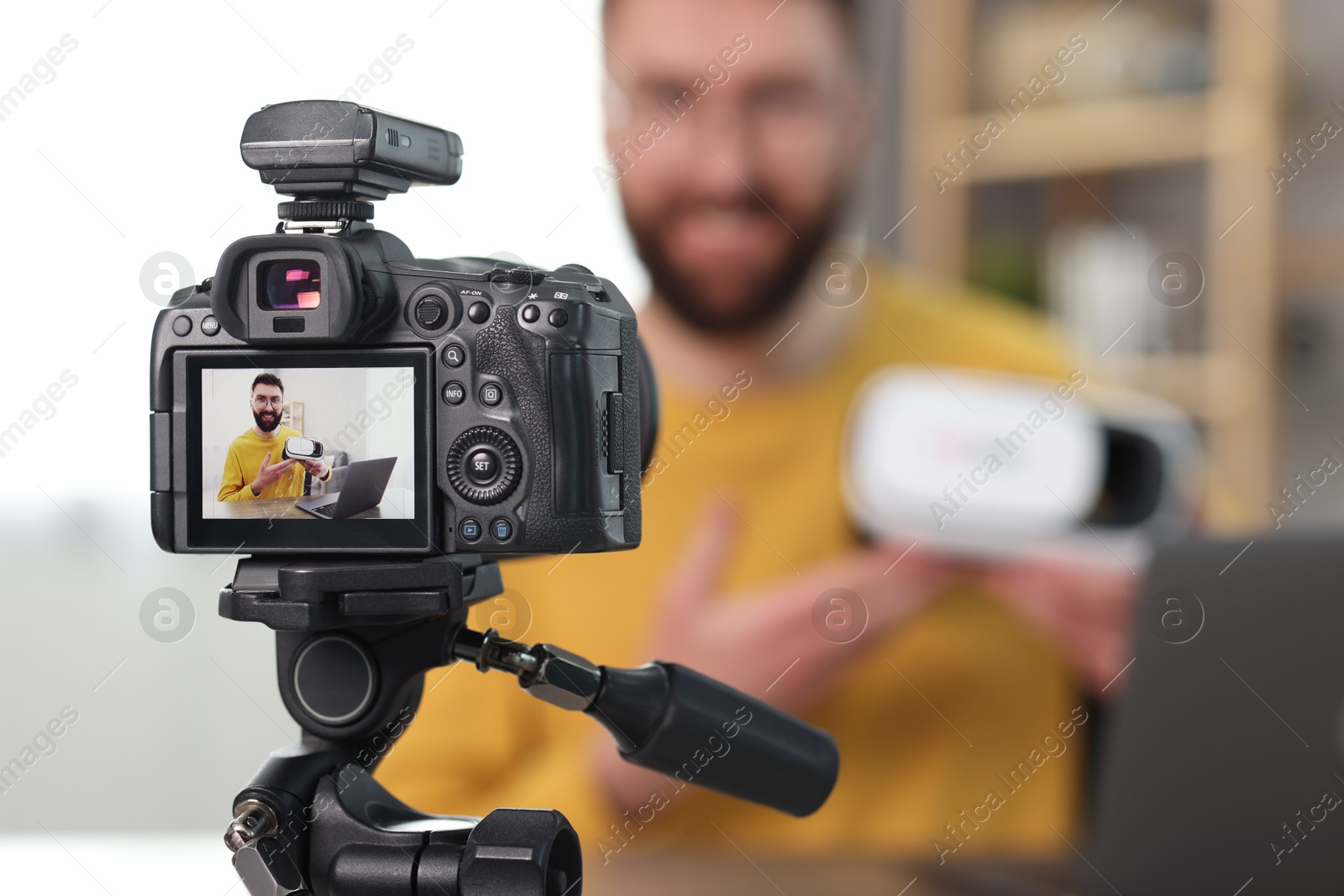 Photo of Technology blogger explaining something while recording video at home, focus on camera