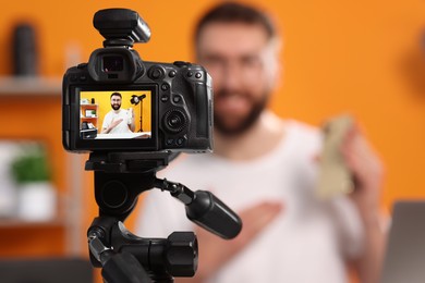 Technology blogger explaining something while recording video at home, focus on camera