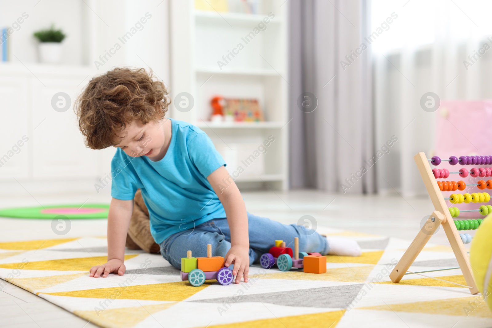 Photo of Cute little boy playing with toy cars on floor in kindergarten