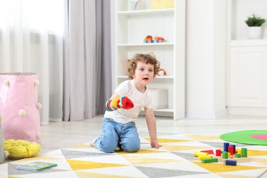 Cute little boy playing with funny sock puppet on floor in kindergarten