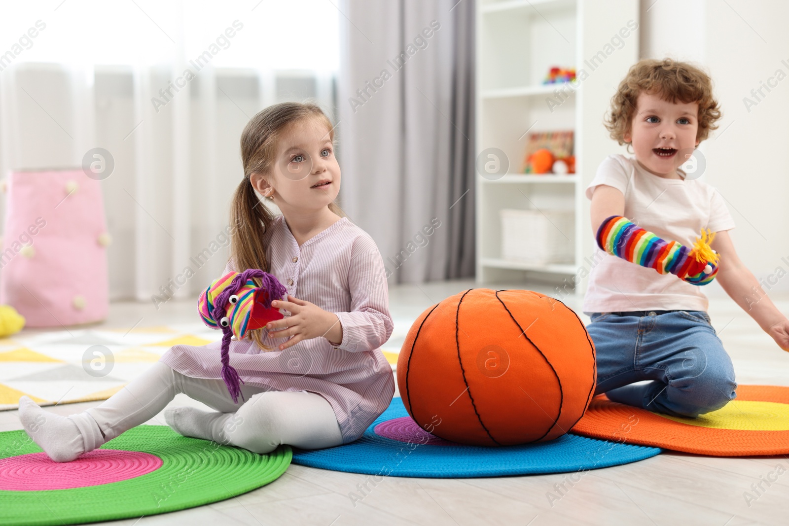 Photo of Cute little children playing with funny sock puppets and soft toy ball in kindergarten