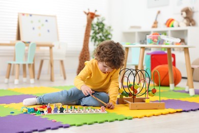 Cute little boy playing with math game Fishing for Numbers on puzzle mat in kindergarten