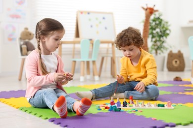 Cute little children playing with math game Fishing for Numbers on puzzle mat in kindergarten