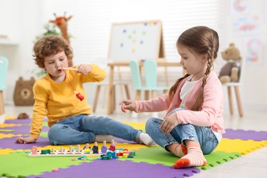 Cute little children playing with math game Fishing for Numbers on puzzle mat in kindergarten