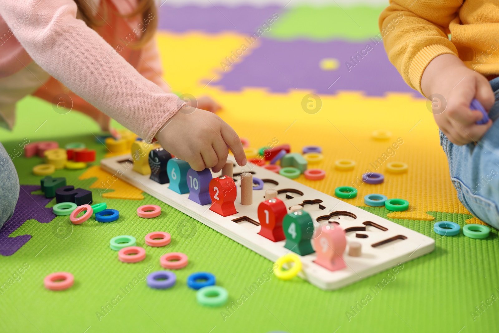 Photo of Little children playing with game Fishing for Numbers on puzzle mat, closeup. Kindergarten activities for learning mathematics