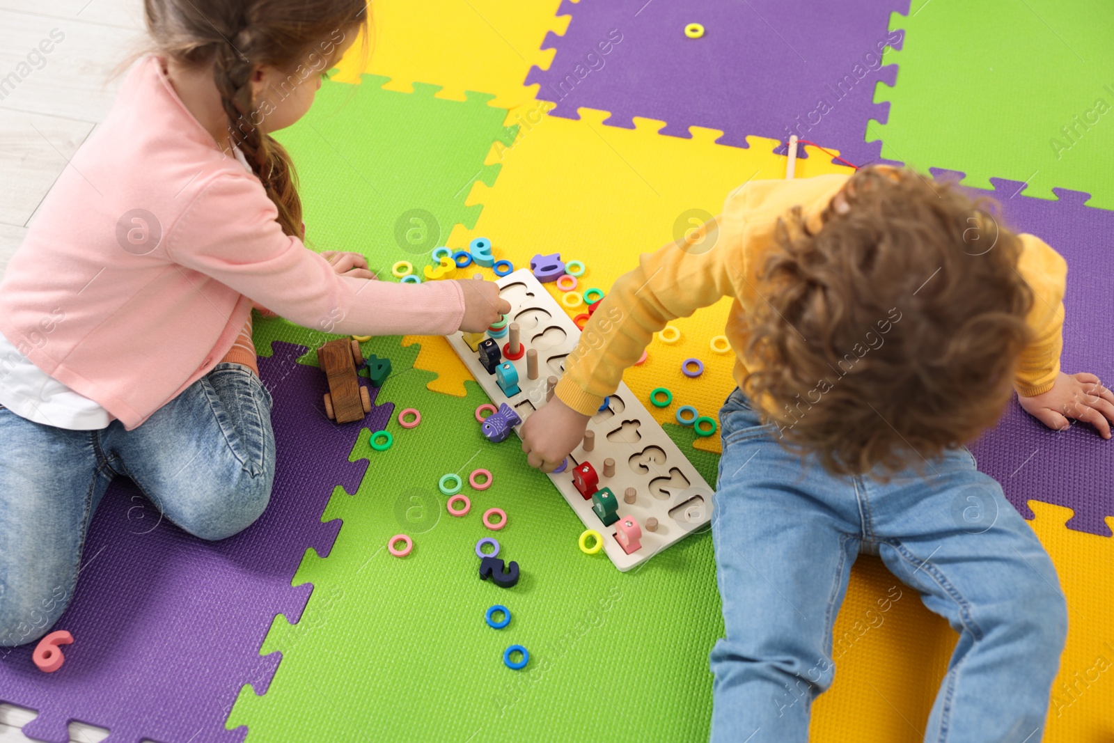 Photo of Cute little children playing with game Fishing for Numbers on puzzle mat. Kindergarten activities for learning mathematics